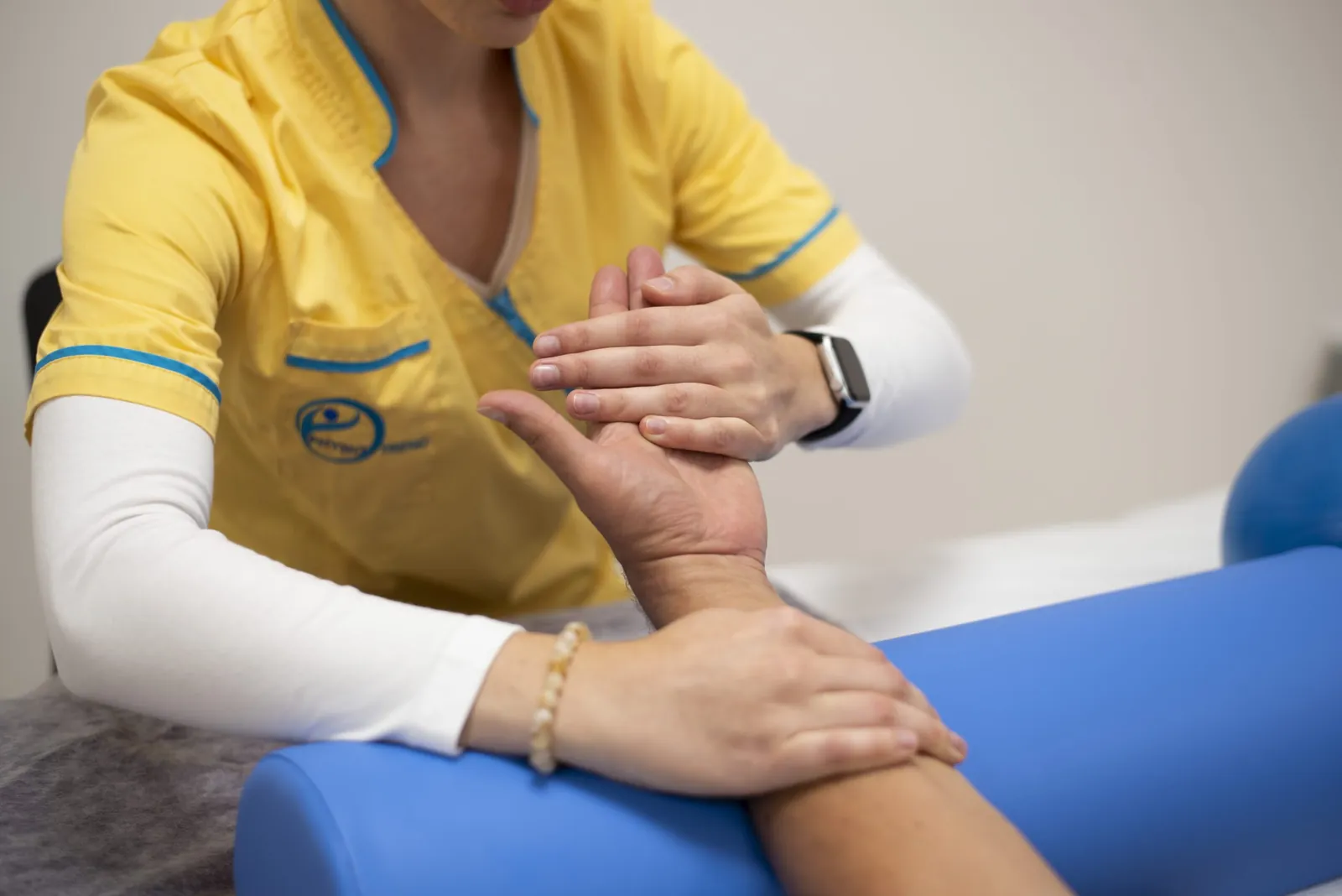 Gyógytornász manuálterápiás vizsgálattal mozgatja a páciens csuklóját